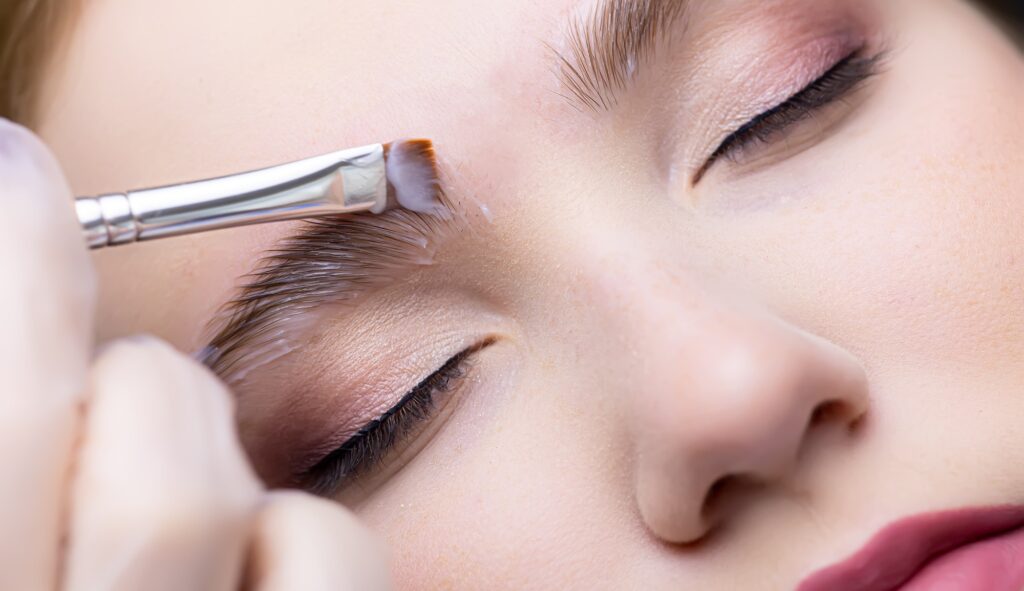 the eyebrows of the model on which the master applies laminating compositions with a brush